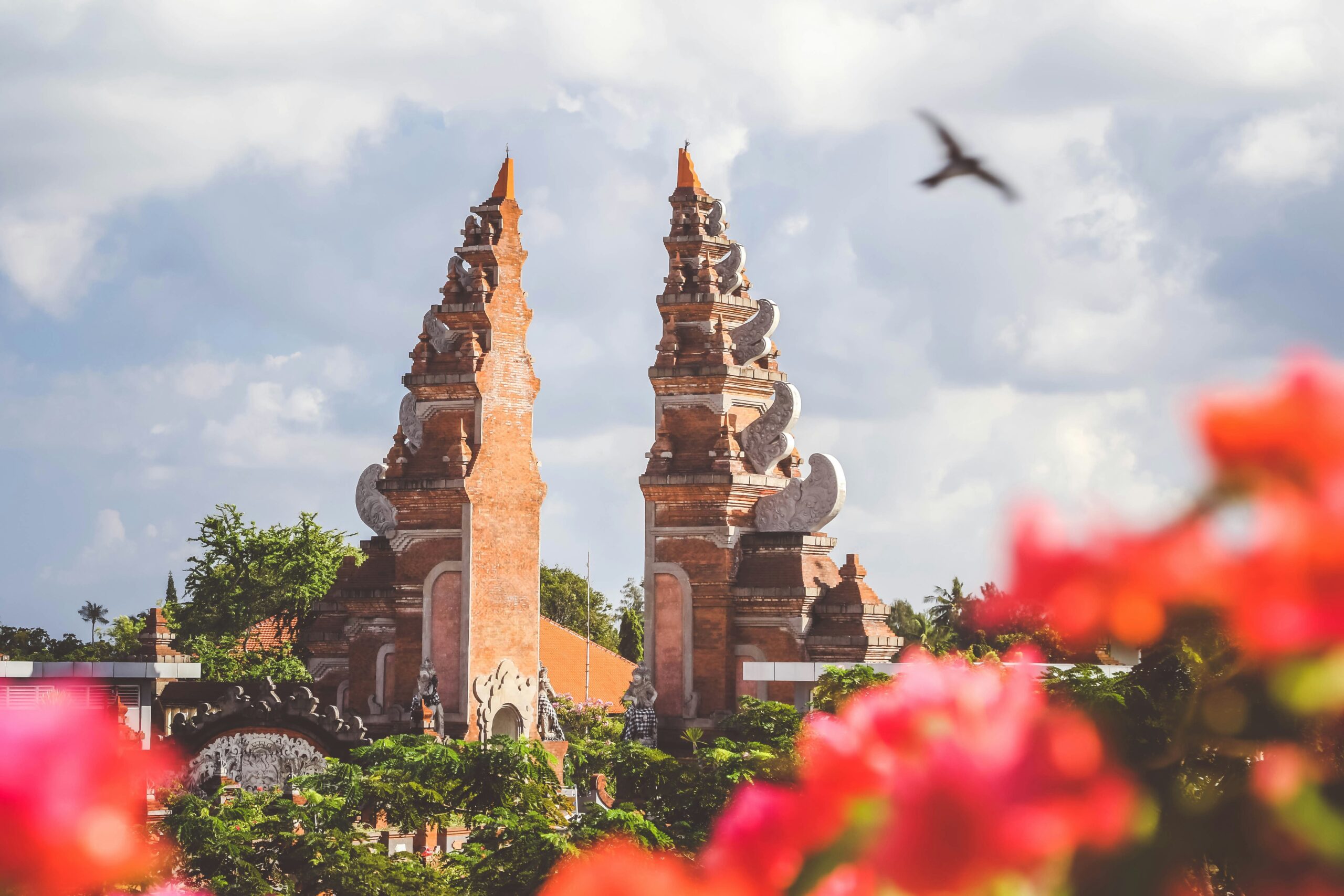 A bird flying over bali's majestic gate